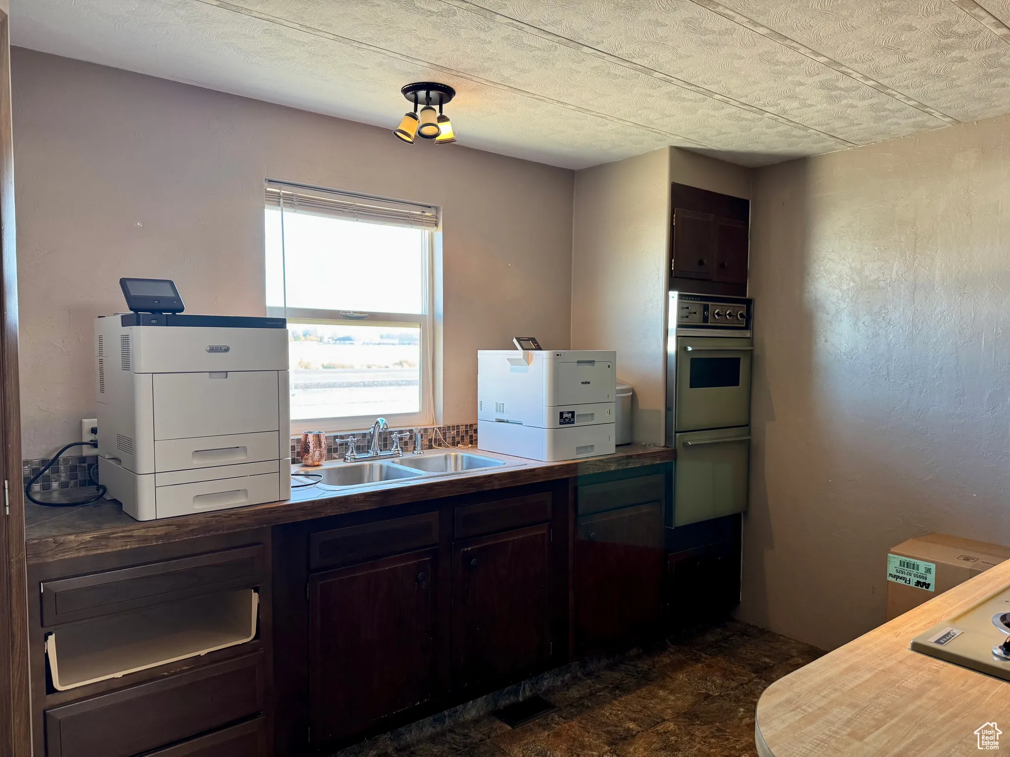 Kitchen with dark brown cabinetry, a textured ceiling, and dark stone finish floors