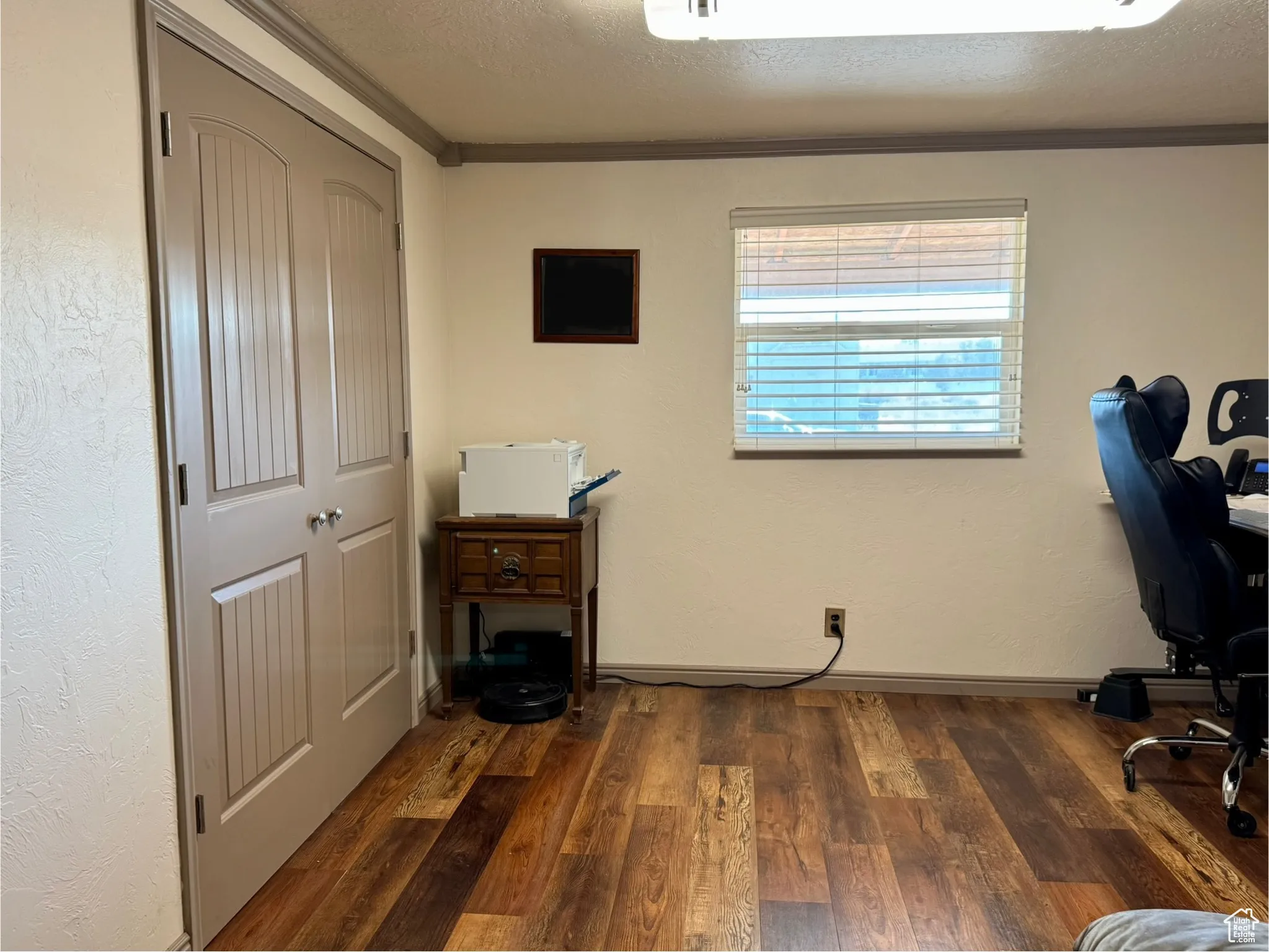 Office with dark wood finished floors, a textured ceiling, and ornamental molding