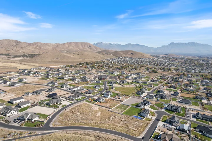 Aerial view of property and surrounding area featuring nearby suburban area and a mountainous background