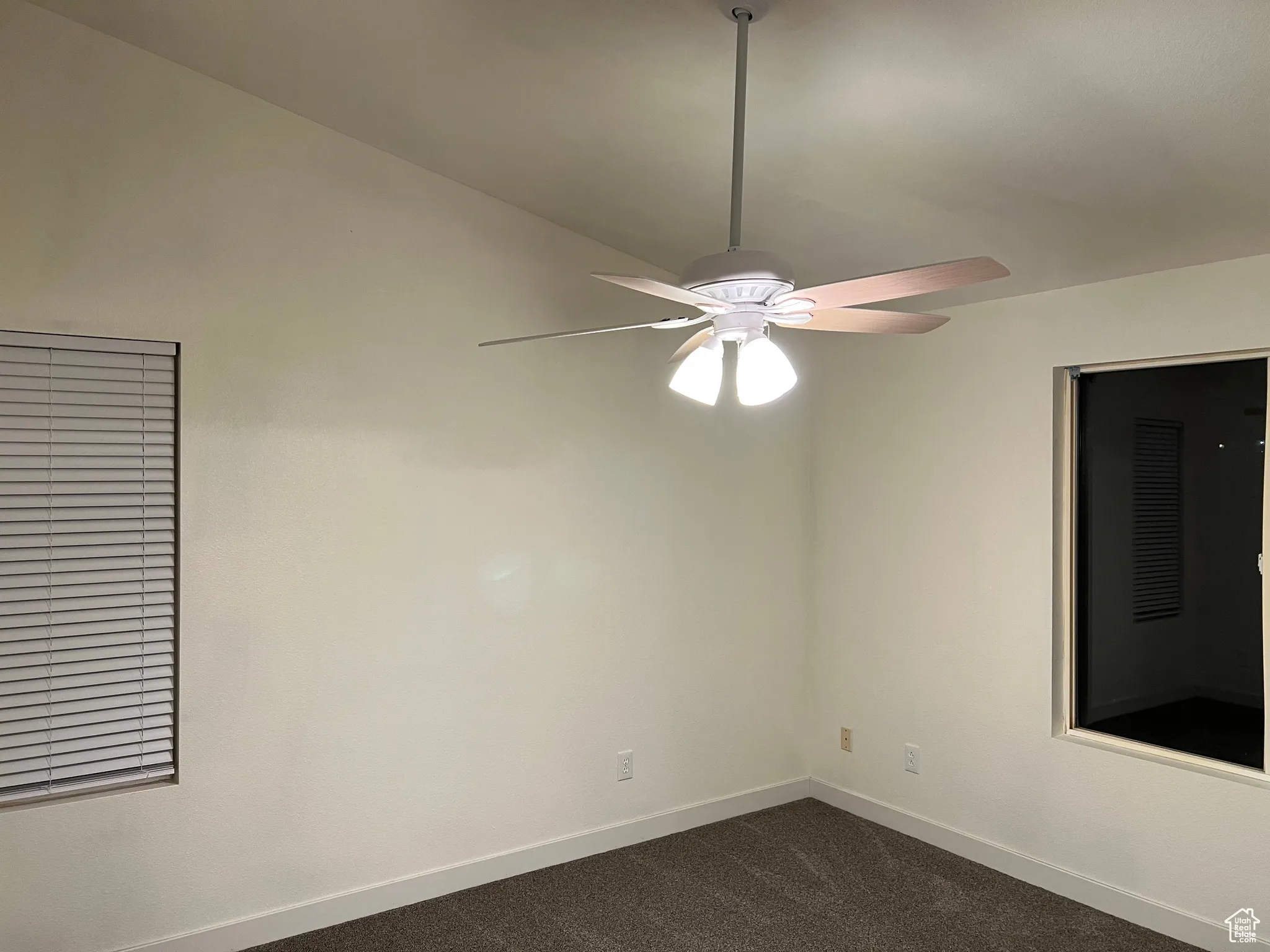 Master bedroom with dark carpet and a ceiling fan.  Back blind will be installed soon