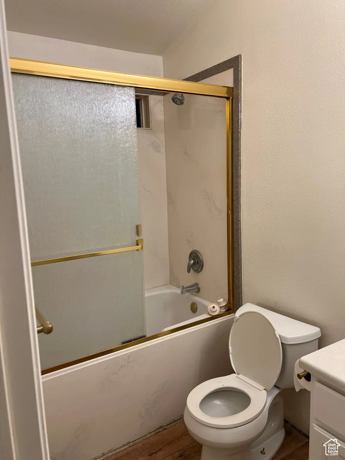 Master bathroom featuring vanity, a textured wall, shower / bath combination with glass door, and wood finished floors