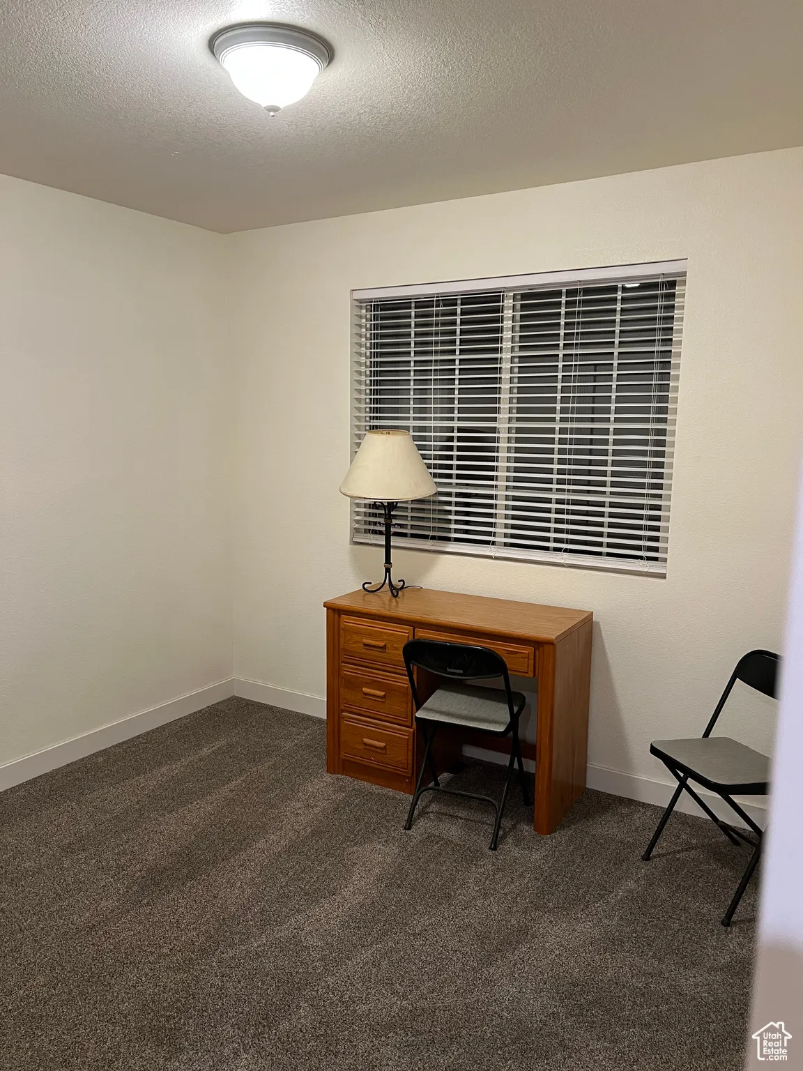 Bedroom 2 with dark colored carpet and a textured ceiling