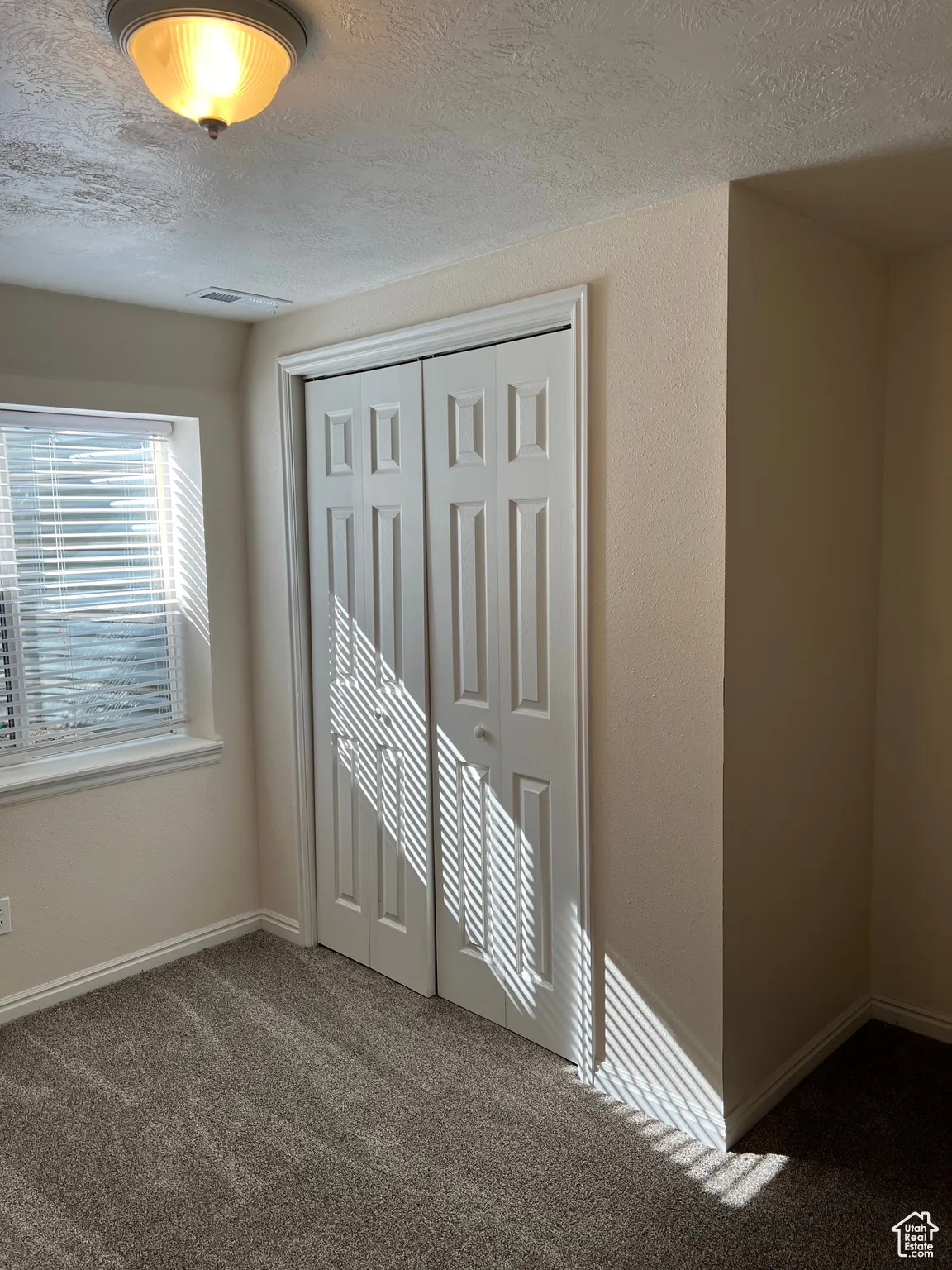 Bedroom 4 featuring dark carpet, a textured ceiling, and a closet