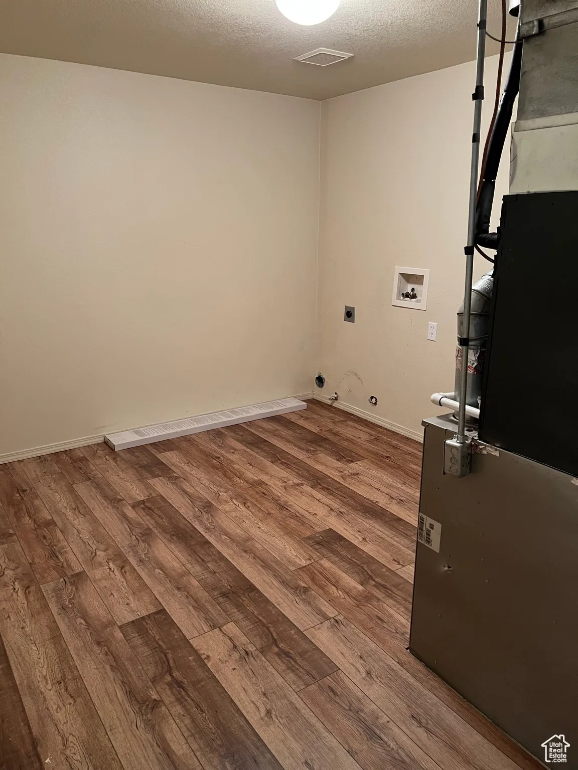 Laundry room featuring a textured ceiling, dark wood finished floors, washer hookup, hookup for an electric dryer, and gas dryer hookup