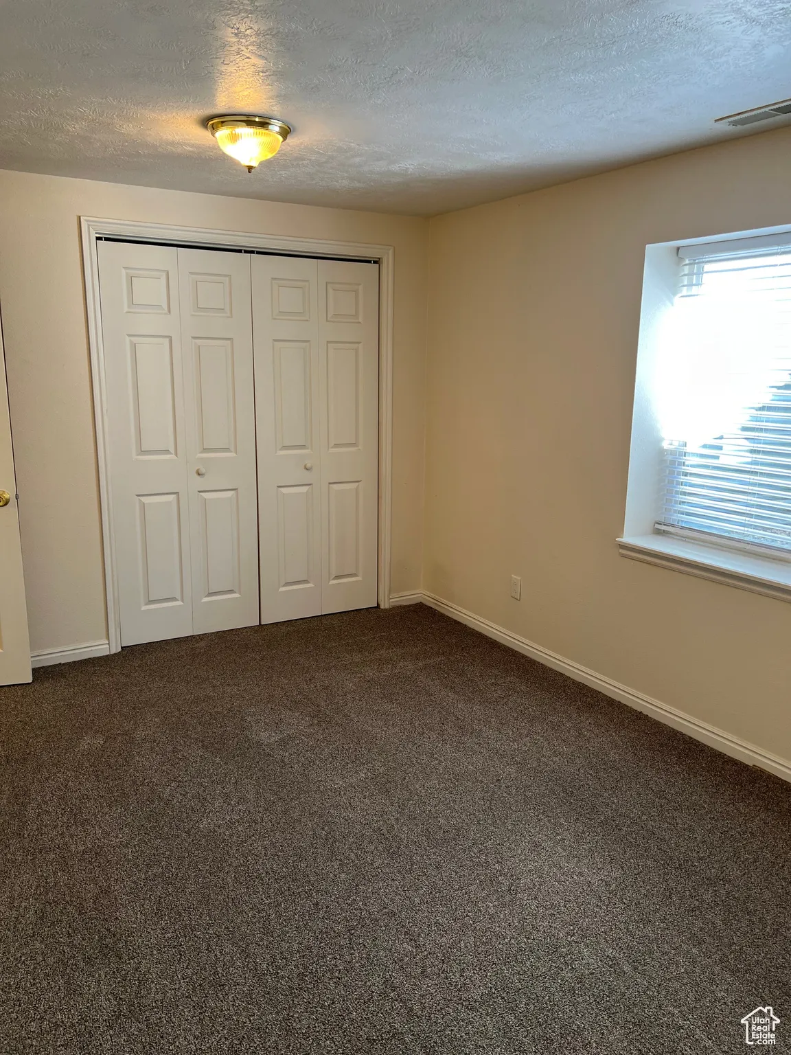 Bedroom 5 with a textured ceiling, dark colored carpet, and a closet