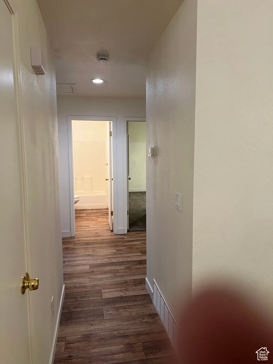 Hall with dark wood-style flooring and baseboards
