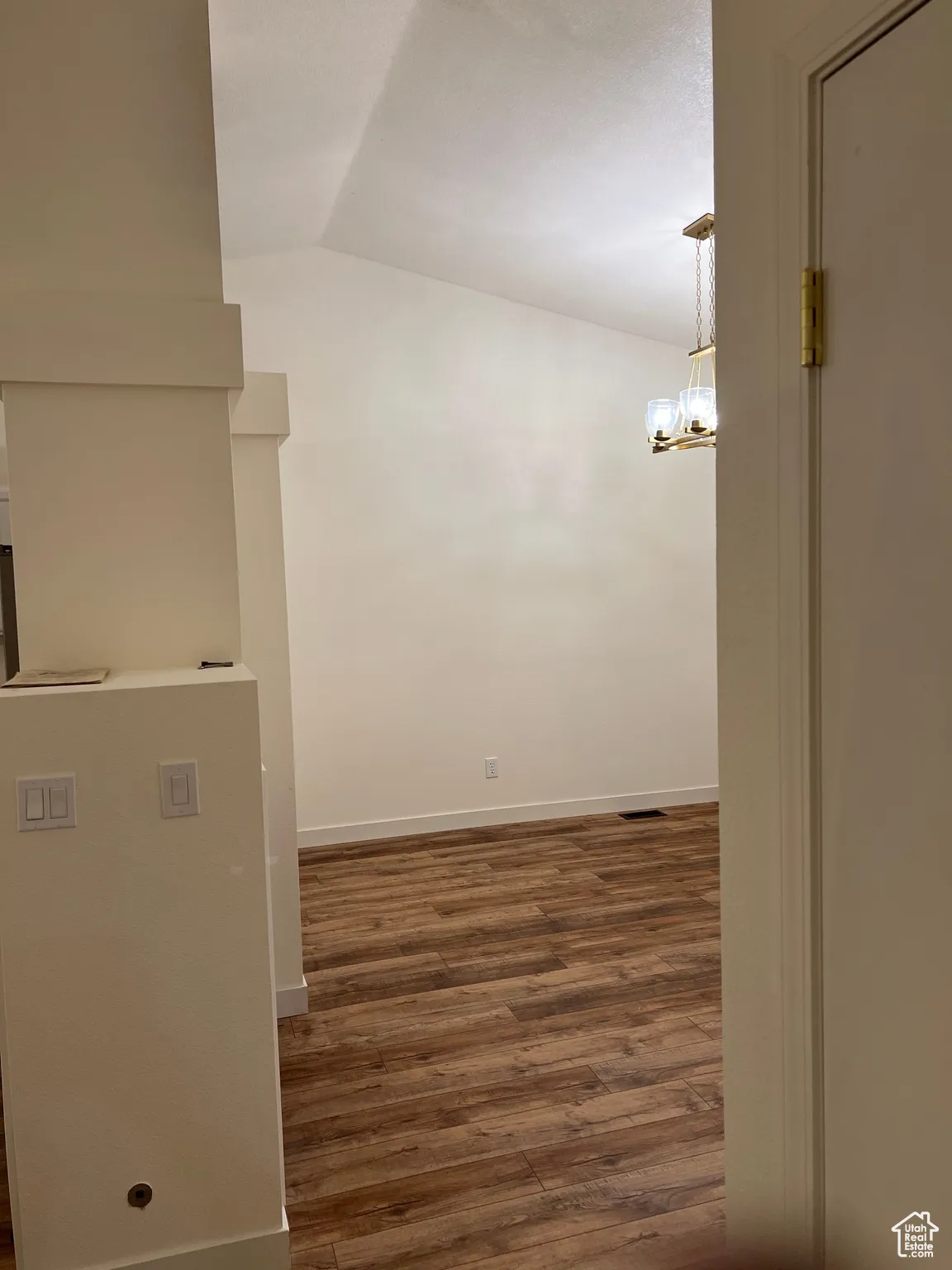 Corridor with lofted ceiling, dark wood finished floors, and a chandelier