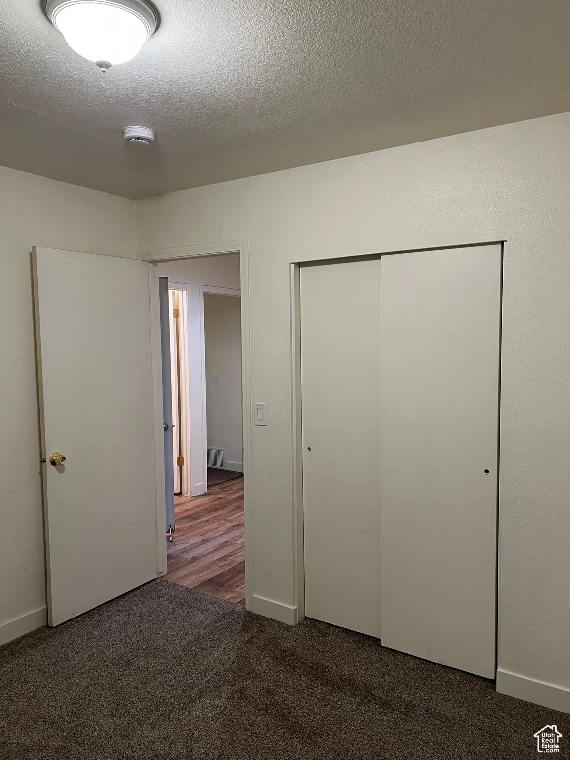 Bedroom 2 with dark carpet, a textured ceiling, and a closet