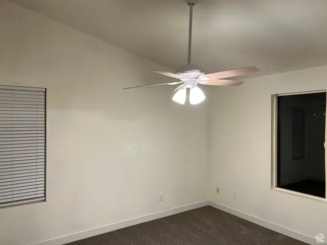 Master bedroom with dark carpet and a ceiling fan.  Back blind will be installed soon