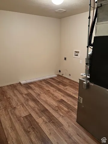 Laundry room featuring a textured ceiling, dark wood finished floors, washer hookup, hookup for an electric dryer, and gas dryer hookup