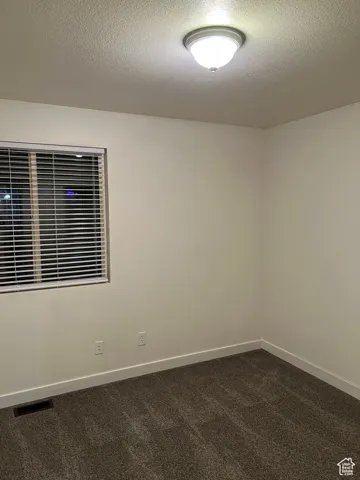 Bedroom 3 room featuring dark carpet and a textured ceiling