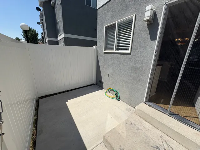 Private patio featuring concrete flooring and a white vinyl fence
