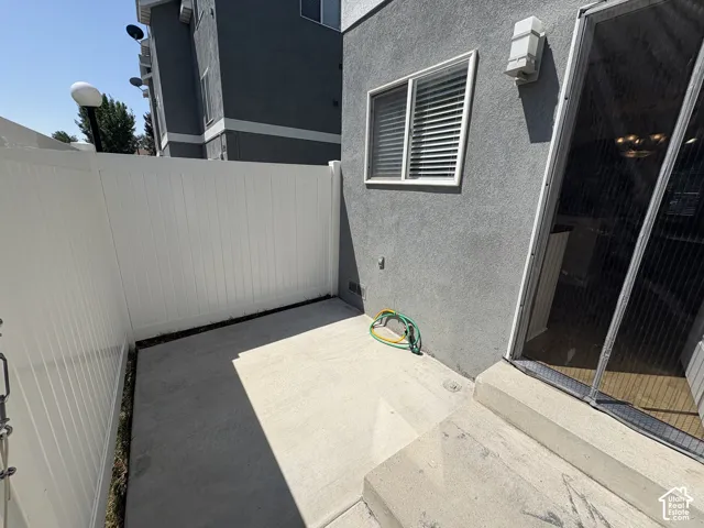 Private patio featuring concrete flooring and a white vinyl fence