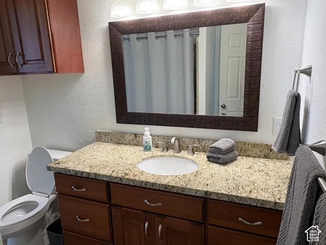 Bathroom vanity featuring a granite countertop with an integrated sink, wood-finish cabinetry, and a framed mirror
