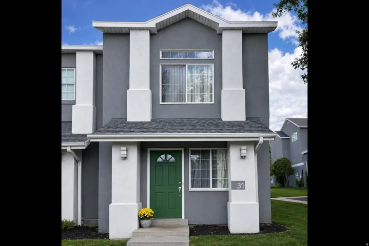 Contemporary facade featuring a prominent green entry door, contrasting grey stucco, white architectural pillars, and dark shingle roofing