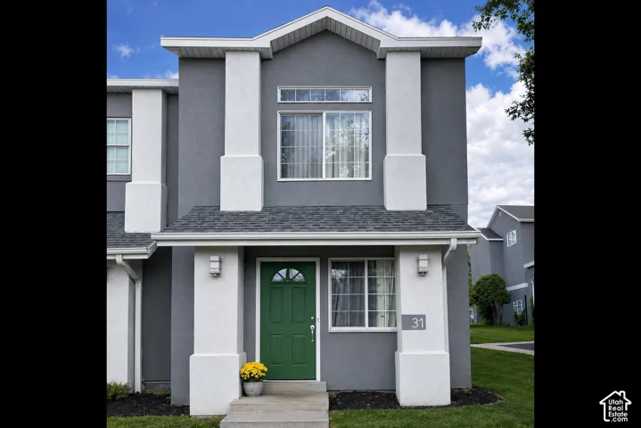 Contemporary facade featuring a prominent green entry door, contrasting grey stucco, white architectural pillars, and dark shingle roofing