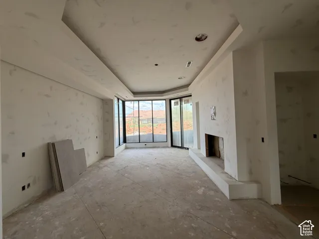 Tray ceiling with recessed lighting, floor-to-ceiling windows, and built-in masonry fireplace hearth
