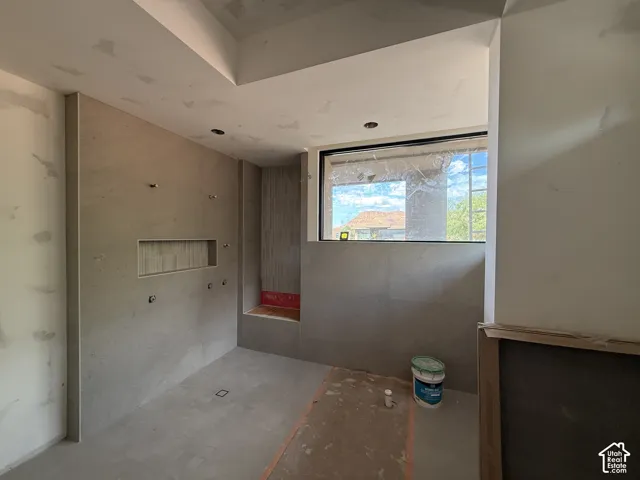 Large-format tile wall surfacing, built-in recessed wall niche, tiled corner seating ledge, and expansive rectangular window featuring a black frame