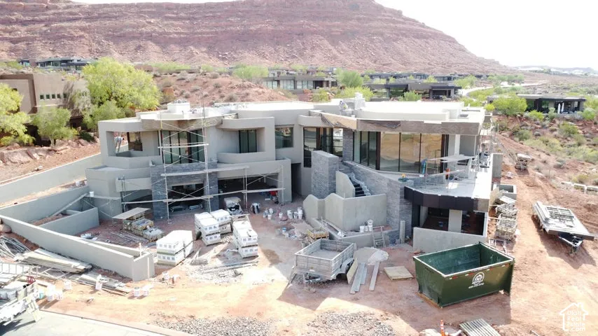 Multi-level exterior featuring stucco and stacked-stone cladding, floor-to-ceiling glass windows, cantilevered balcony structures, and an integrated multi-car garage
