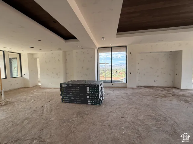 Interior space featuring recessed tray ceilings with dark wood-tone inlays, expansive floor-to-ceiling windows, and recessed lighting