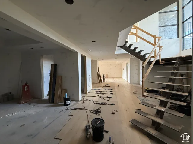 Open-concept interior featuring wood-finish flooring, a metal floating staircase with wooden treads, floor-to-ceiling windows, and recessed lighting