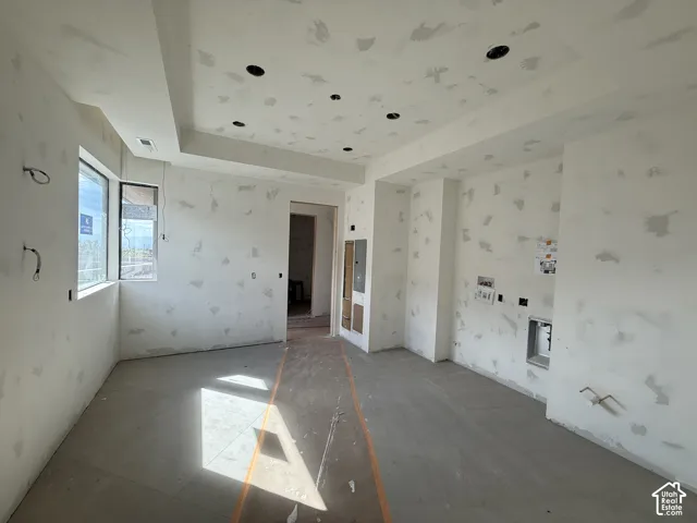 Interior space featuring a recessed tray ceiling, multiple inset ceiling light fixtures, large window, and plumbing hookups