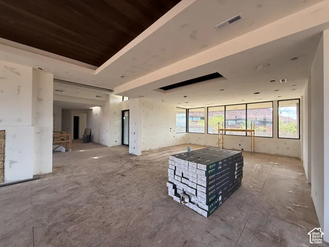 Open-concept interior featuring a recessed wood-paneled ceiling detail, tiered tray ceiling, and floor-to-ceiling windows with black frames