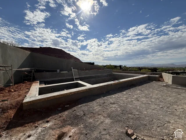 In-ground concrete pool structure with integrated spa, masonry retaining walls, and desert landscape backdrop