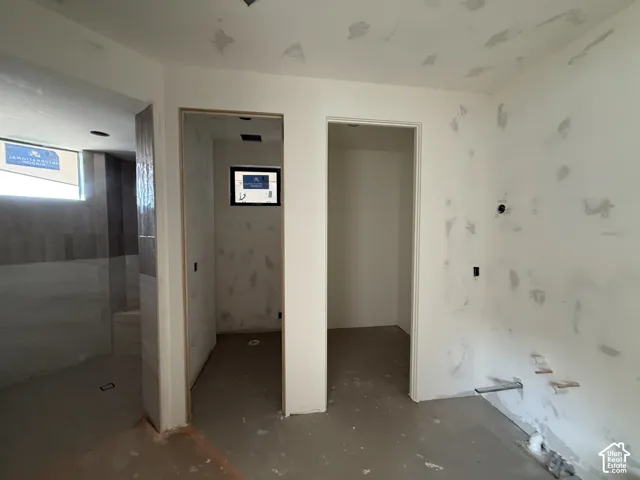 Interior space featuring tiled shower area with built-in bench, two separate doorways, and wall-mounted plumbing rough-ins