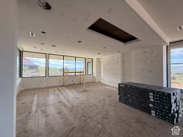 Open-concept room featuring floor-to-ceiling windows, a recessed tray ceiling with wood-finish detailing, and integrated recessed lighting