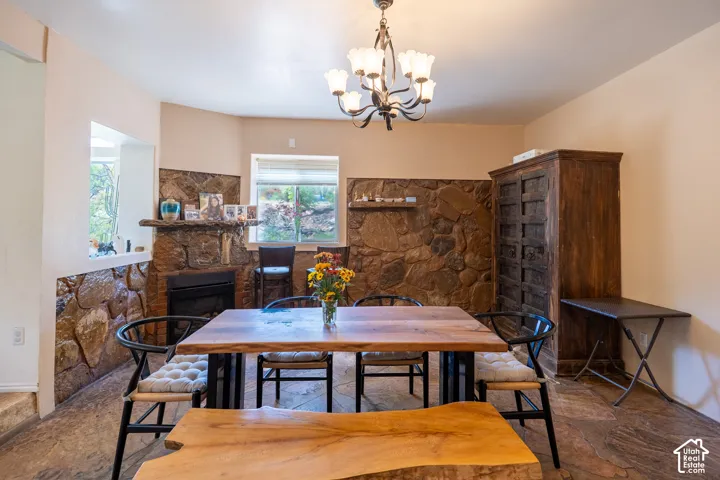 Dining area featuring stone tile floors, a fireplace, and a chandelier