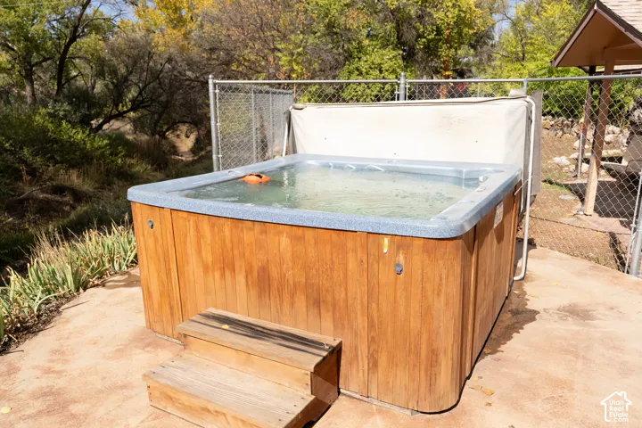 View of patio / terrace with a hot tub and view of wooded area