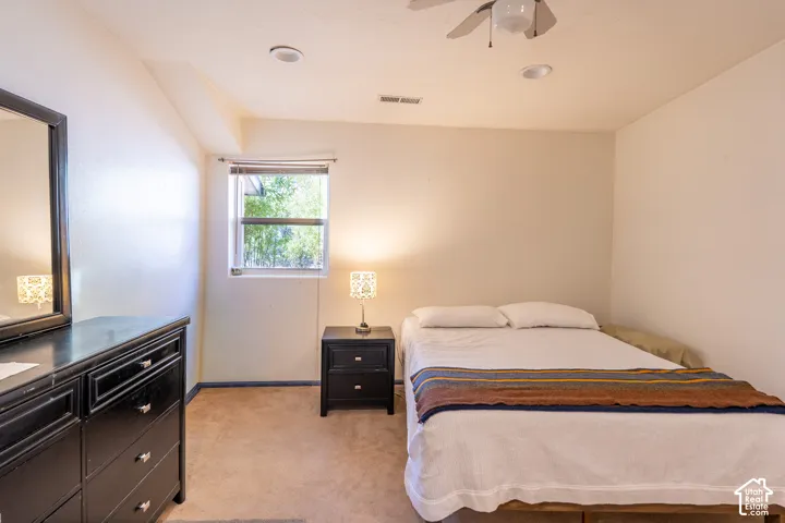 Bedroom featuring light carpet, ceiling fan, and vaulted ceiling