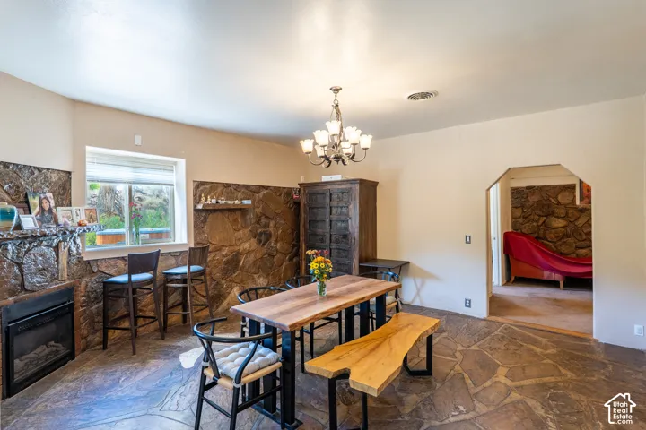 Dining area with stone flooring, a fireplace, a chandelier, and arched walkways