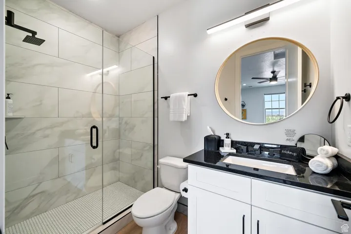 Bathroom featuring a shower stall, vanity, and a ceiling fan