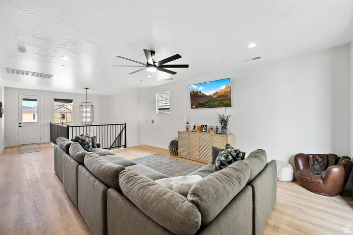 Living room with plenty of natural light, light wood-style floors, a chandelier, ceiling fan, and recessed lighting