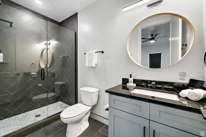 Bathroom with vanity, a stall shower, and a ceiling fan
