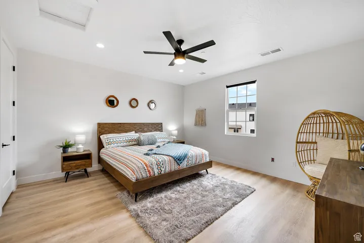 Bedroom with light wood-type flooring, a ceiling fan, attic access, and recessed lighting