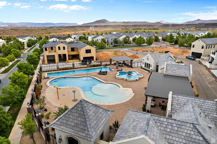 Community pool featuring a patio area, a residential view, a community hot tub, a fenced backyard, and a mountain view