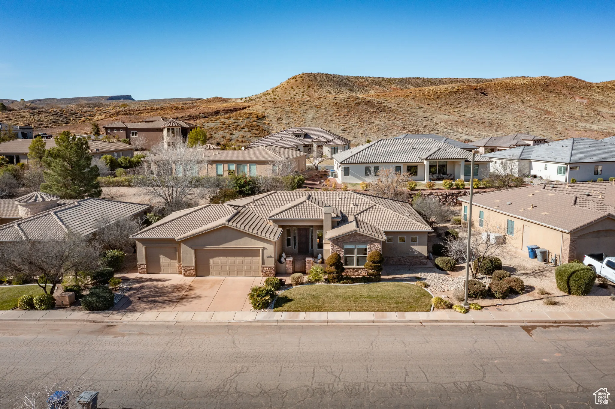 View of front of house with stone siding, a garage, concrete driveway, a residential view, and a mountain view