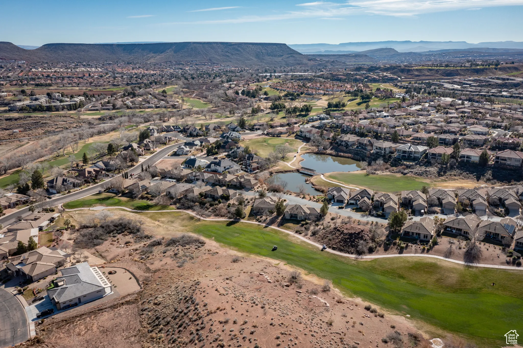 Aerial view of property and surrounding area with a water and mountain view, nearby suburban area, and a local golf course