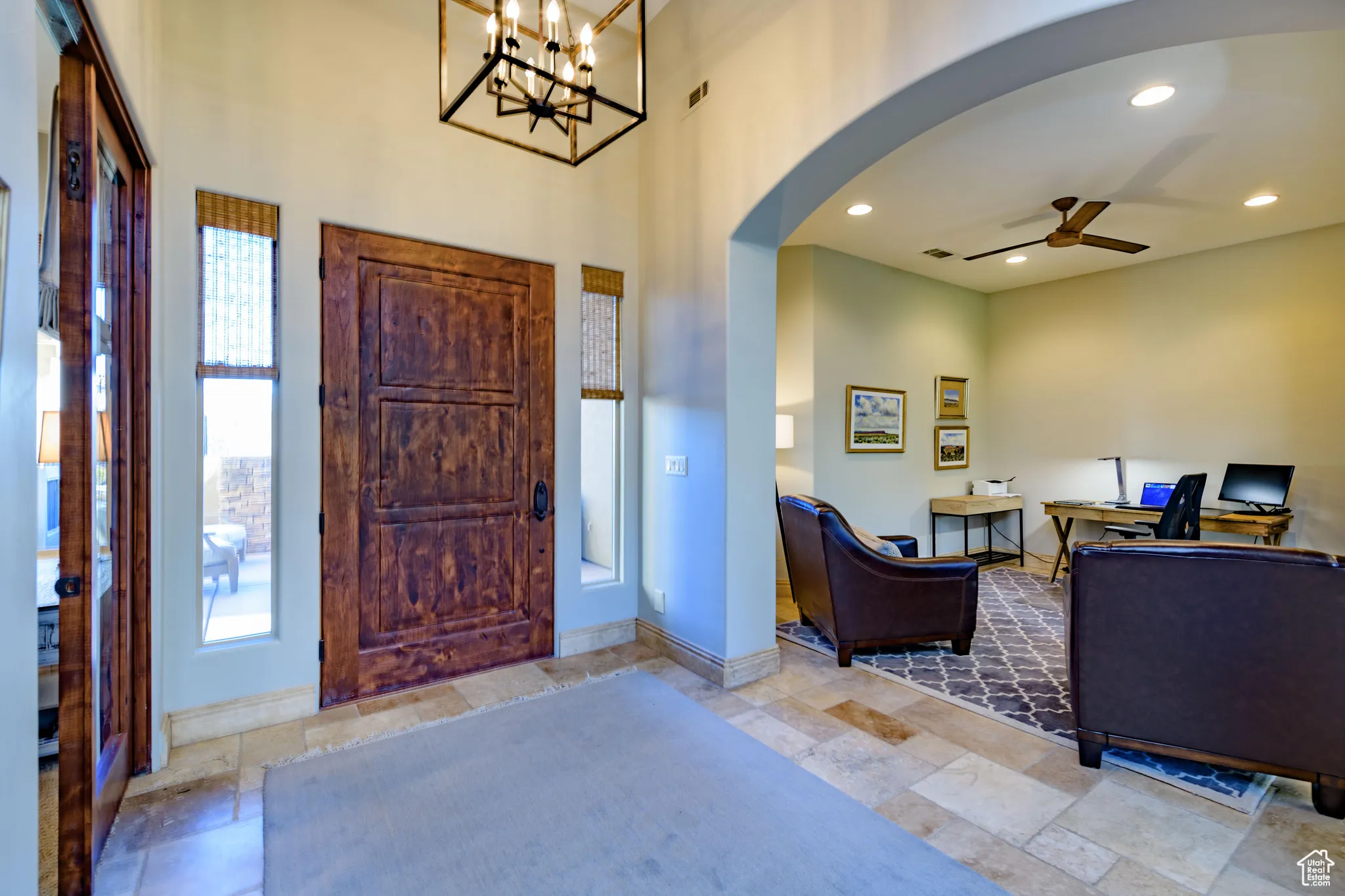Entryway with ceiling fan, recessed lighting, stone tile flooring, arched walkways, and a chandelier