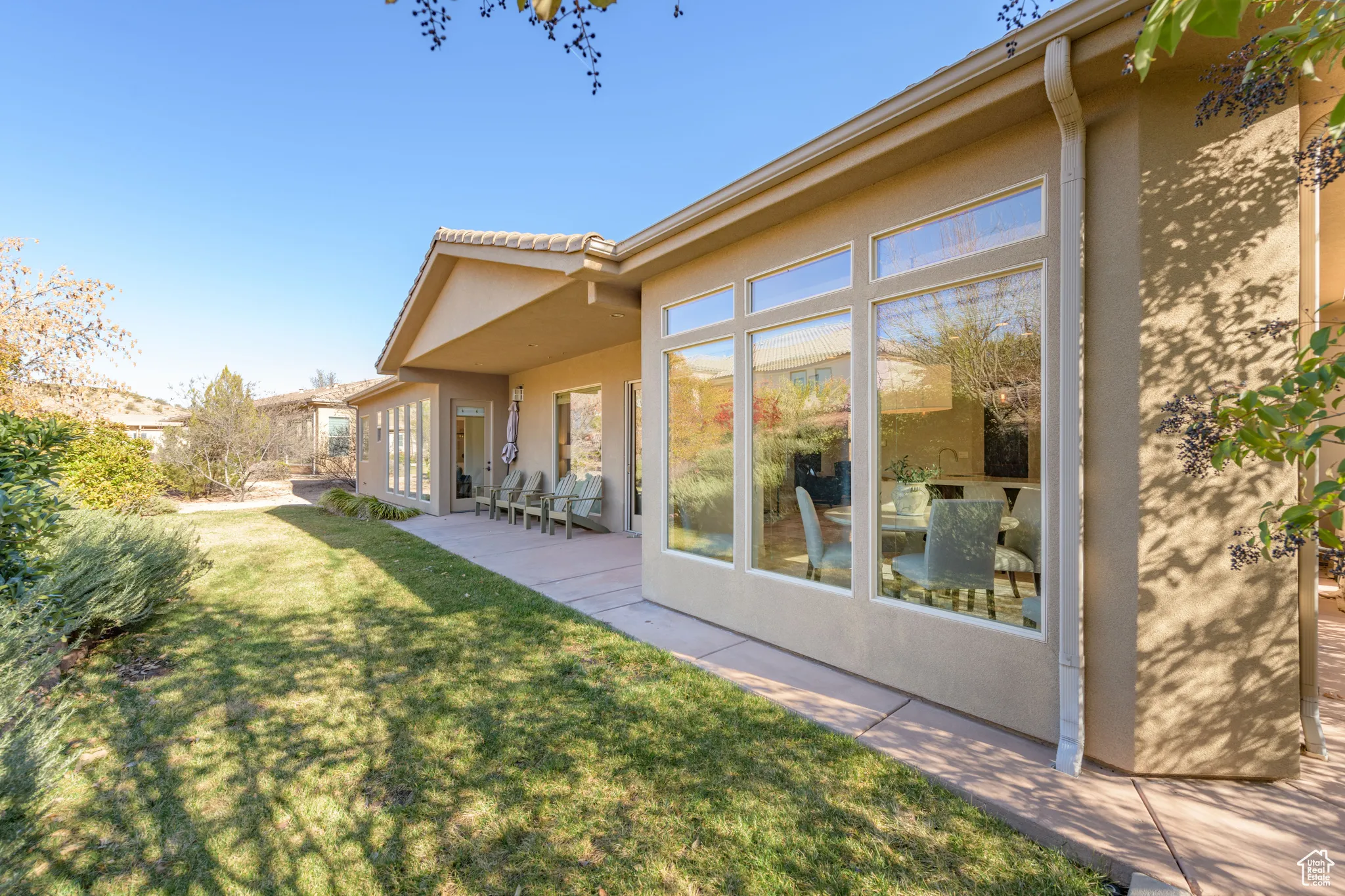 Rear view of property with a yard, stucco siding, and a patio