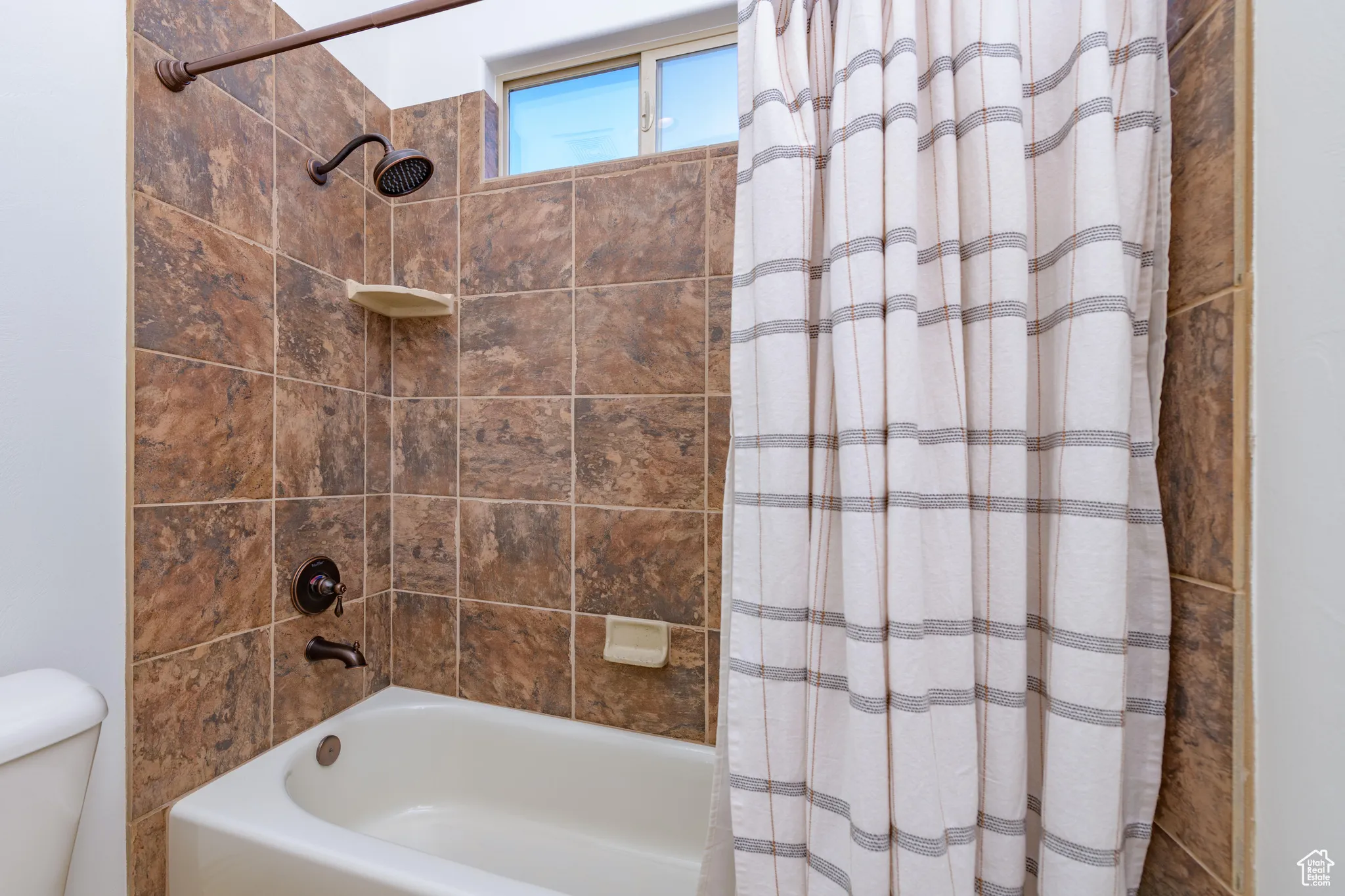 Full bathroom featuring shower / bath combination with curtain and toilet