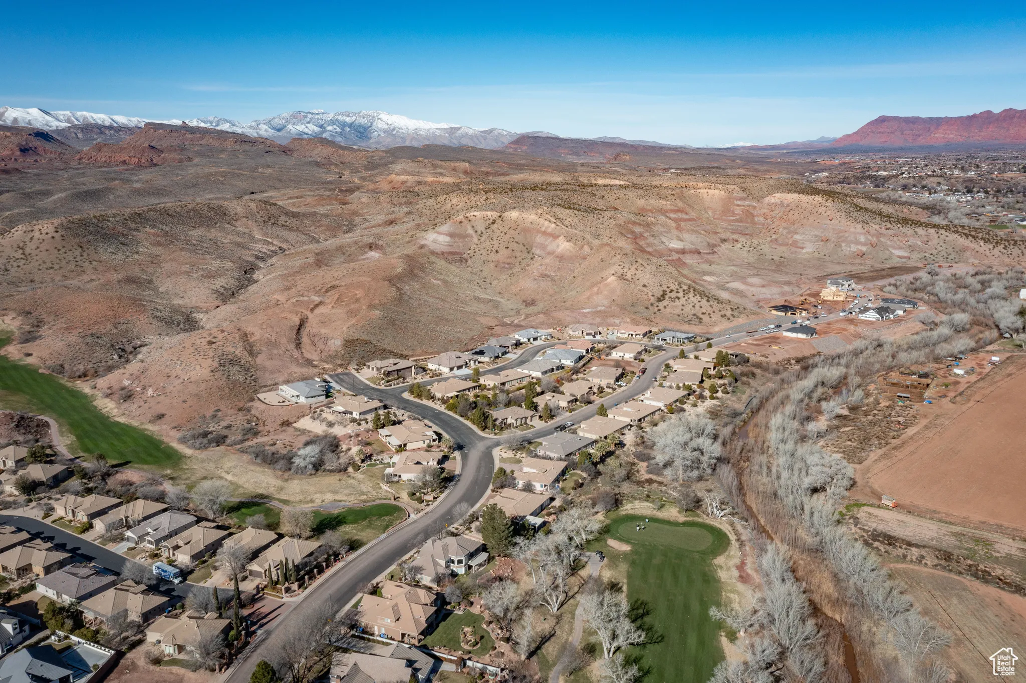 Aerial view of property and surrounding area featuring mountains, nearby suburban area, and a golf club