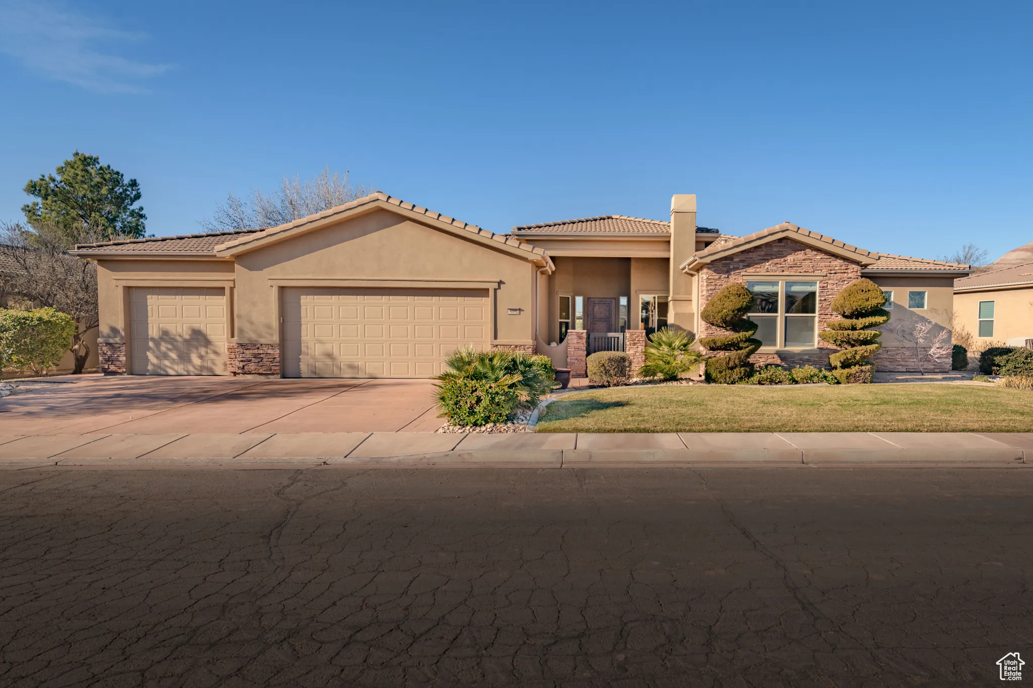 View of front of house with stucco siding, stone siding, a garage, concrete driveway, and a front yard