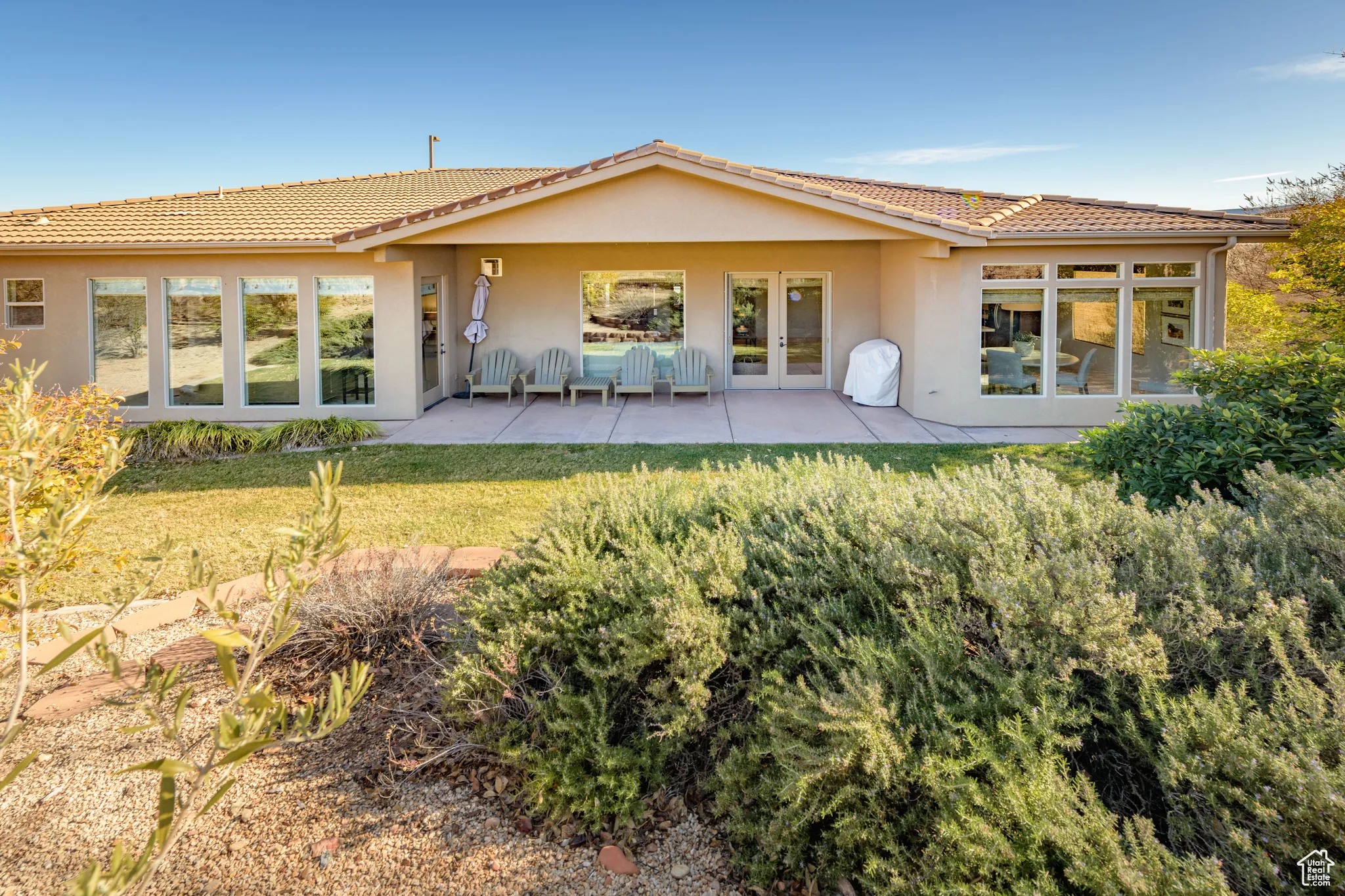 Back of house with stucco siding, a patio, a tile roof, and a yard