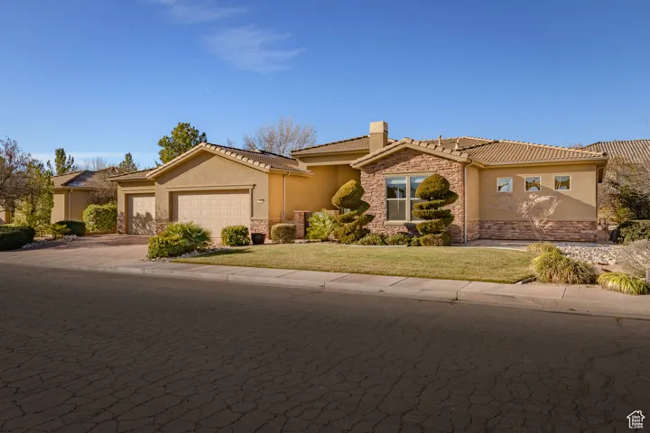 Ranch-style home featuring stone siding, stucco siding, driveway, a garage, and a front yard