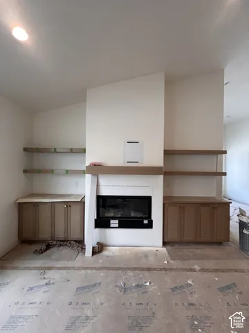Fireplace focal point featuring a contemporary linear insert, wood-finish mantel, recessed cabinetry, and double-tier floating wood-finish shelving under a vaulted ceiling with recessed lighting