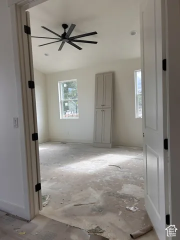 Room featuring a multi-blade ceiling fan, recessed lighting, two windows, and built-in vertical cabinetry